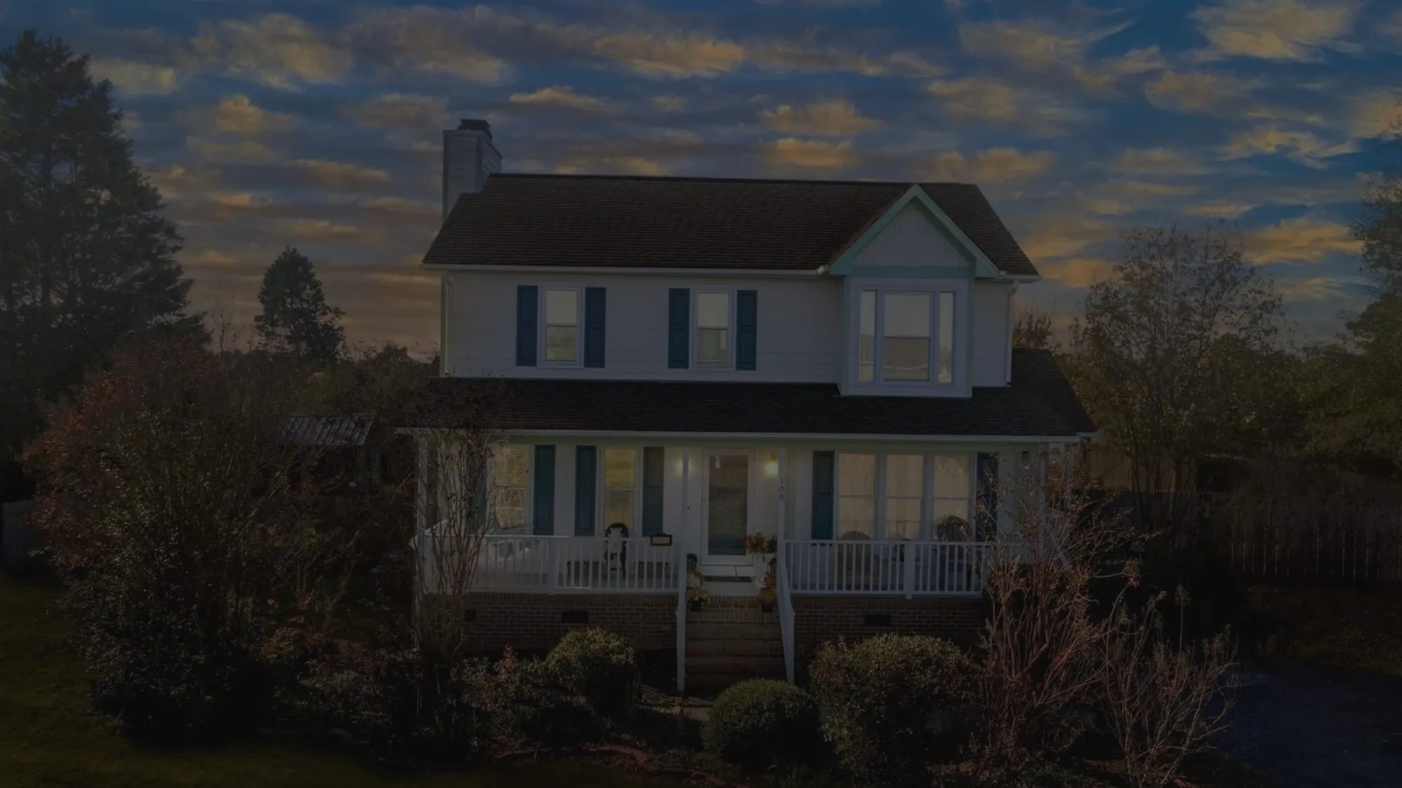 Home with a wraparound porch at sunset, before editing