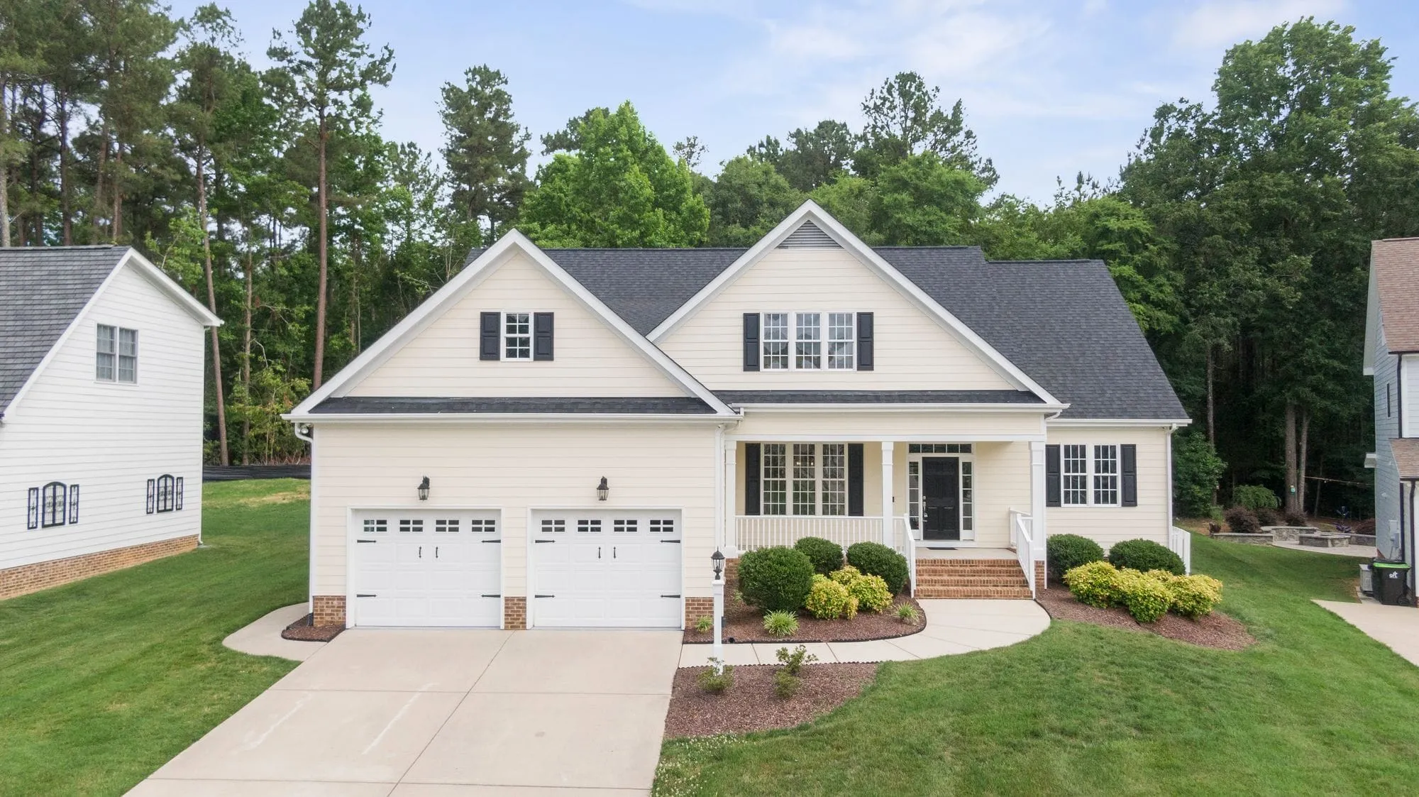 White farmhouse-style home with a two-car garage and a green lawn