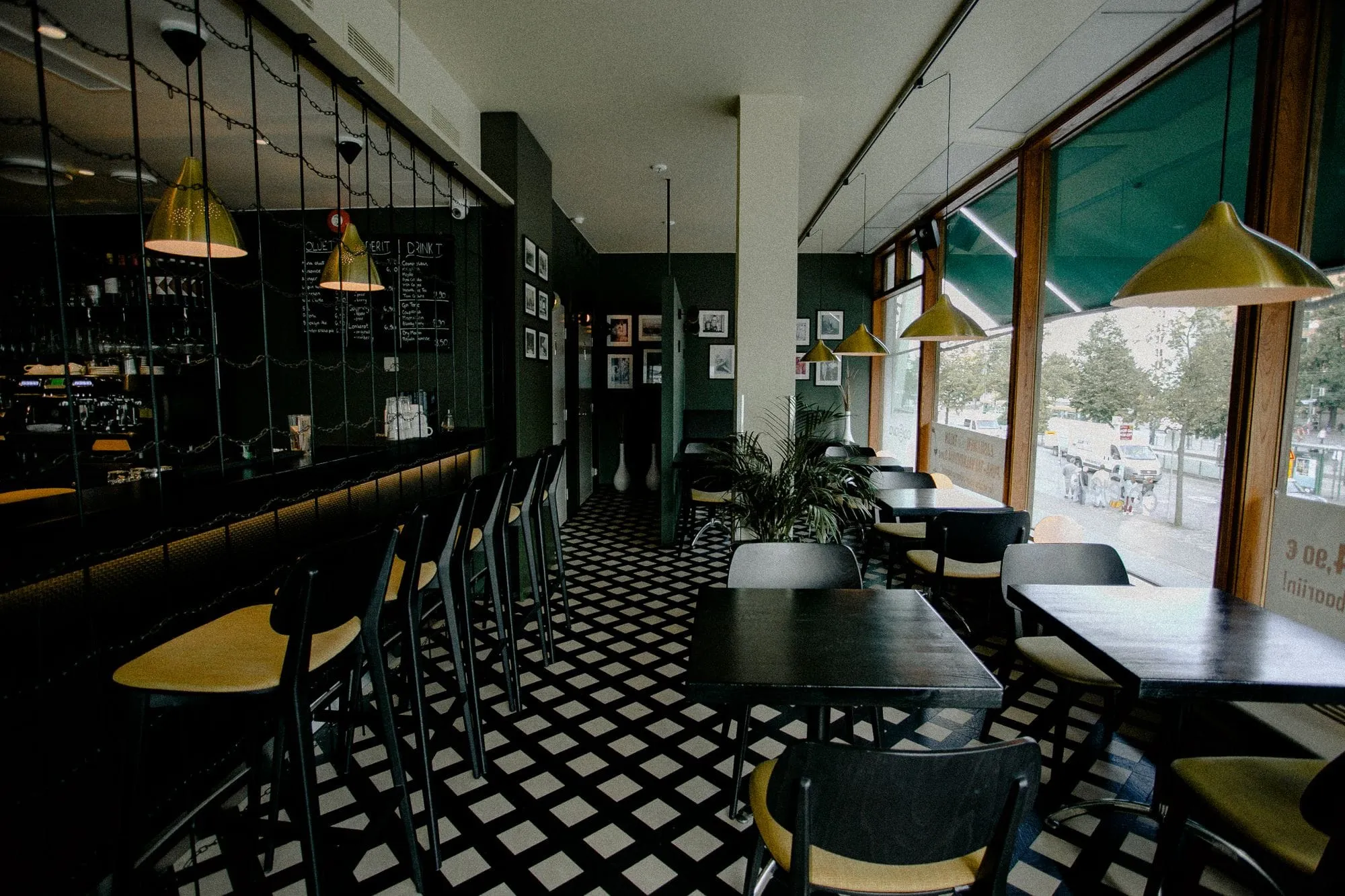 Café with a long bar, pendant lamps and a black-and-white tiled floor