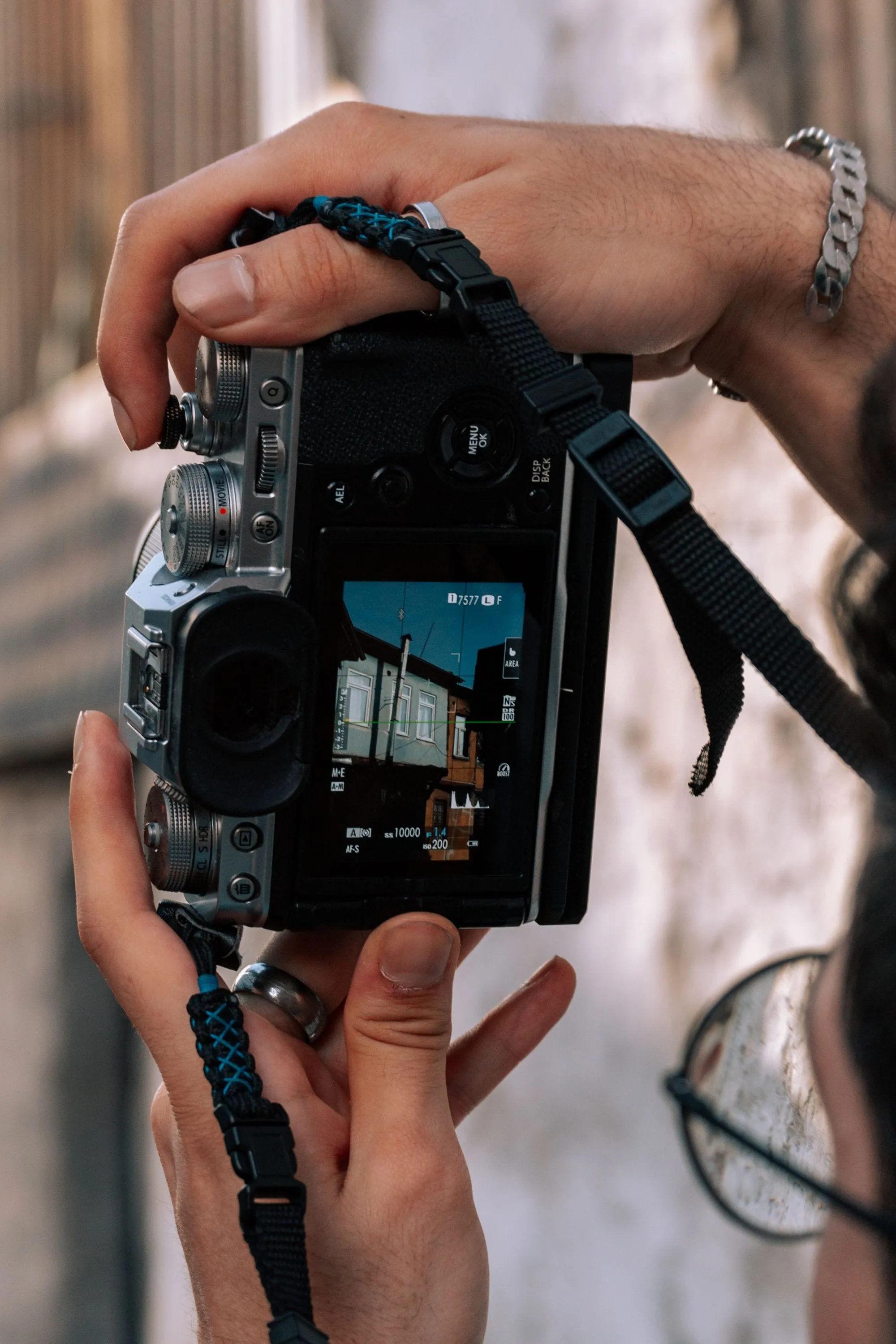 Hands holding a camera with a building facade on its screen